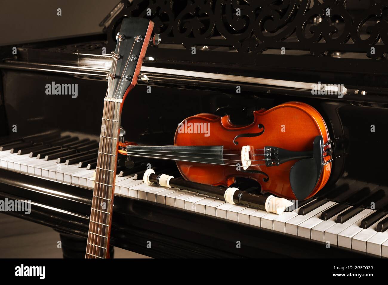 Flute, violin and guitar neck on piano Stock Photo - Alamy