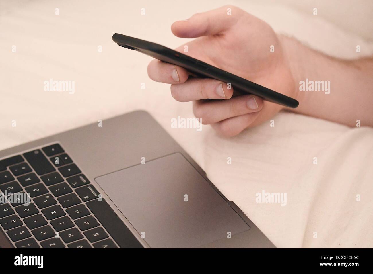 A man using his phone and laptop computer at the same time Stock Photo