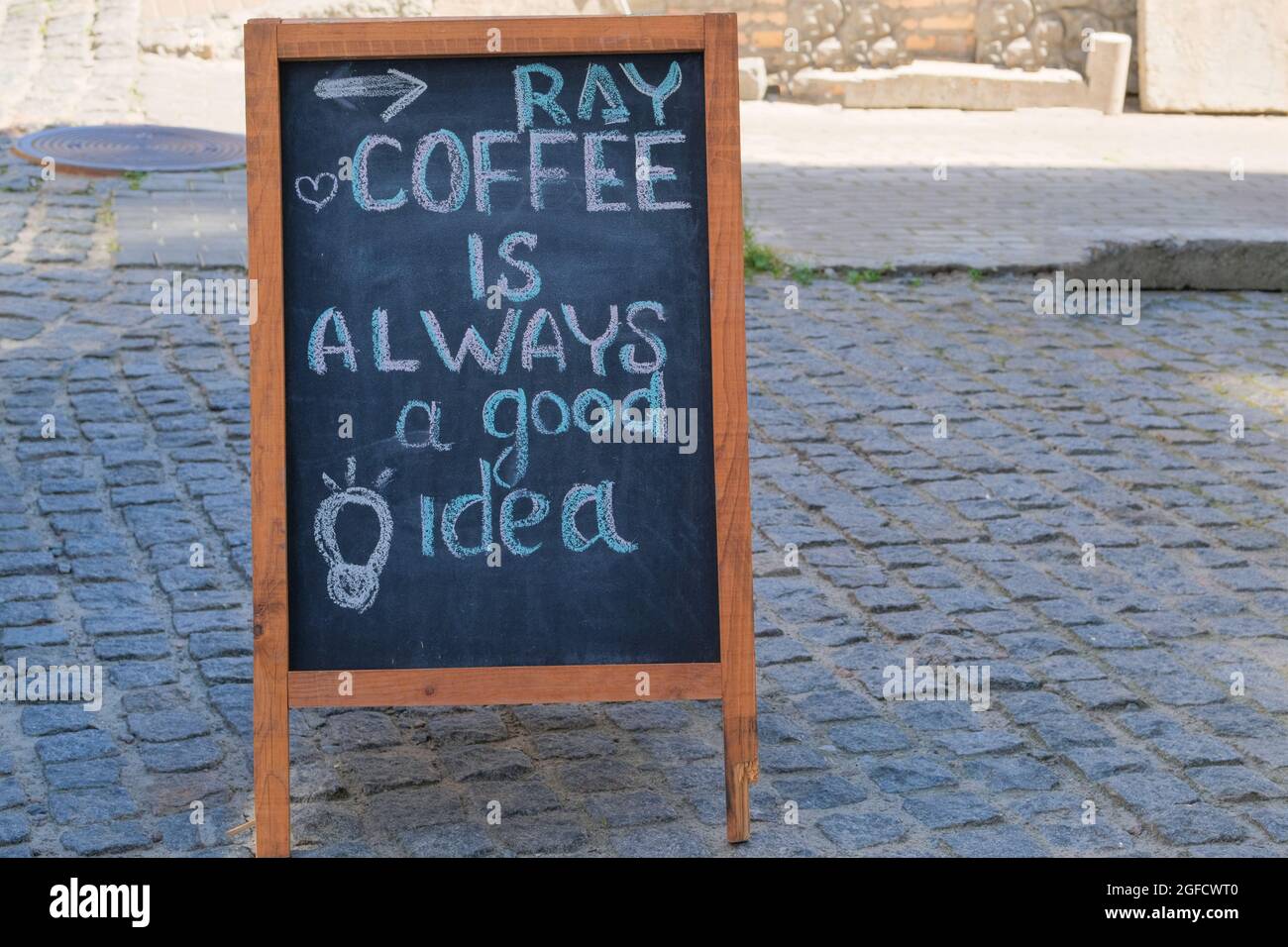 Black board menu black color, message or advertising. Chalkboard is standing near the restaurant. Sunny day. Coffee is always a good idea. Stock Photo
