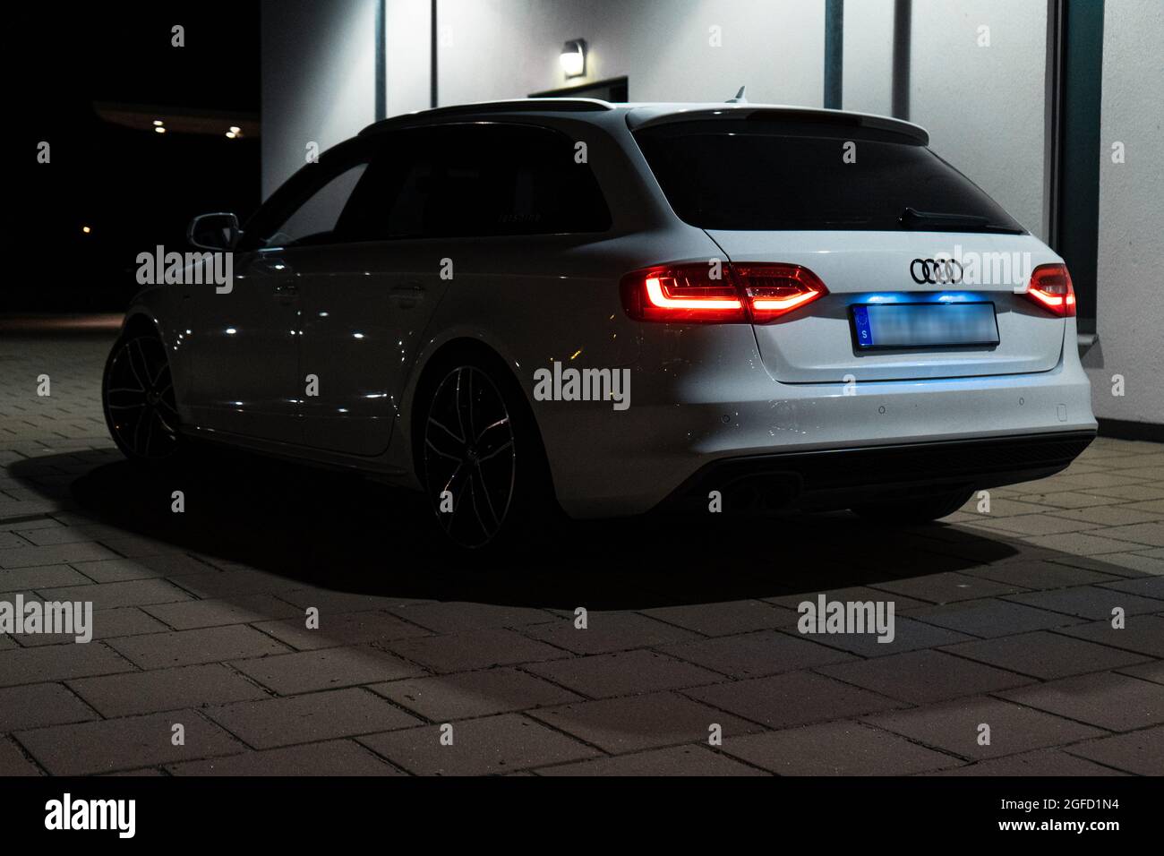 ULRICEHAMN, SWEDEN - Aug 04, 2021: The back part of white Audi A4 Avant with lit taillights outdoors at night Stock Photo