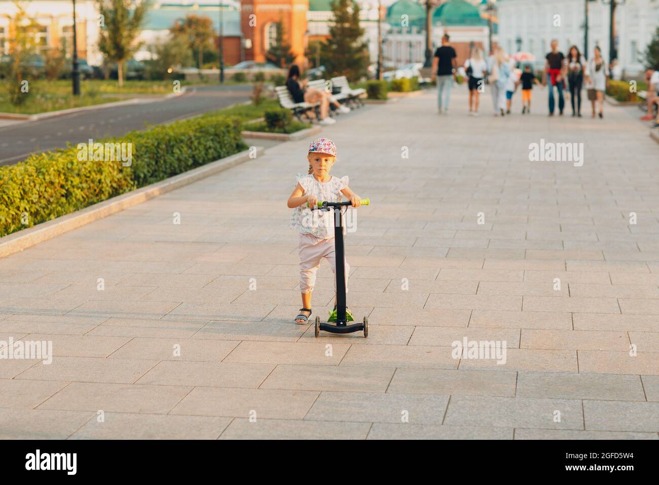 Little girl using a scooter on the city street Stock Photo