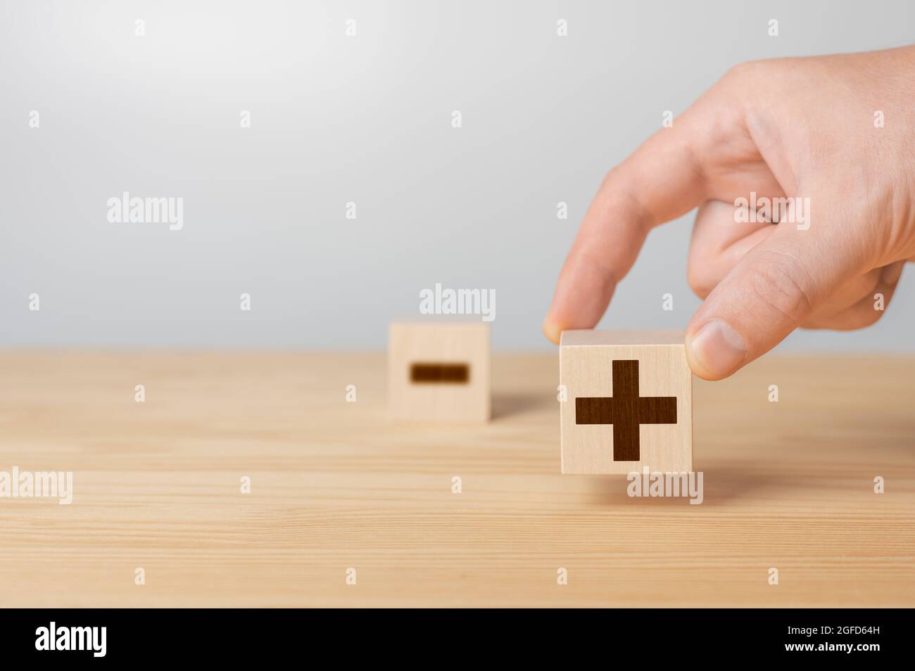Wooden cubes with the image of pros versus cons. Plus or minus. Businessman holds a cubes with plus icon. Wooden cube with minus icon. wooden cubes wi Stock Photo