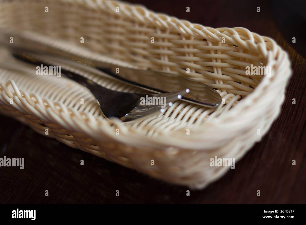 Knife and fork in a basket on a table Stock Photo