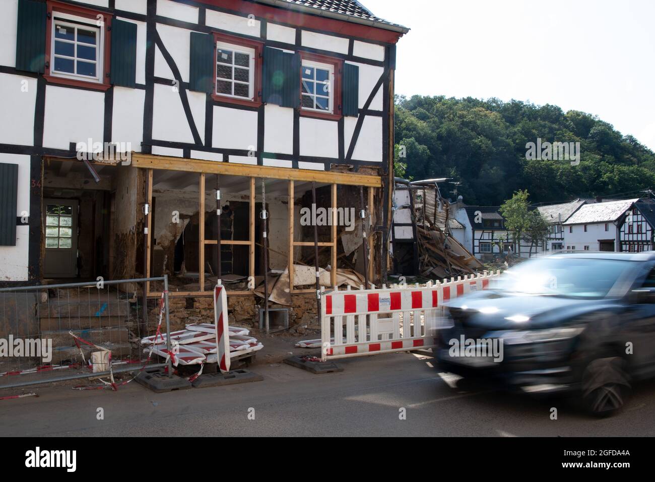 25 August 2021, North Rhine-Westphalia, Bad Münstereifel: A car drives past damaged houses. The flood disaster in mid-July has so far caused insurance losses of around seven billion euros, which is more than previously expected. According to the industry association GDV, 6.5 billion euros of this was attributable to residential buildings, household contents and businesses, and around 450 million euros to motor vehicles. Photo: Federico Gambarini/dpa Stock Photo