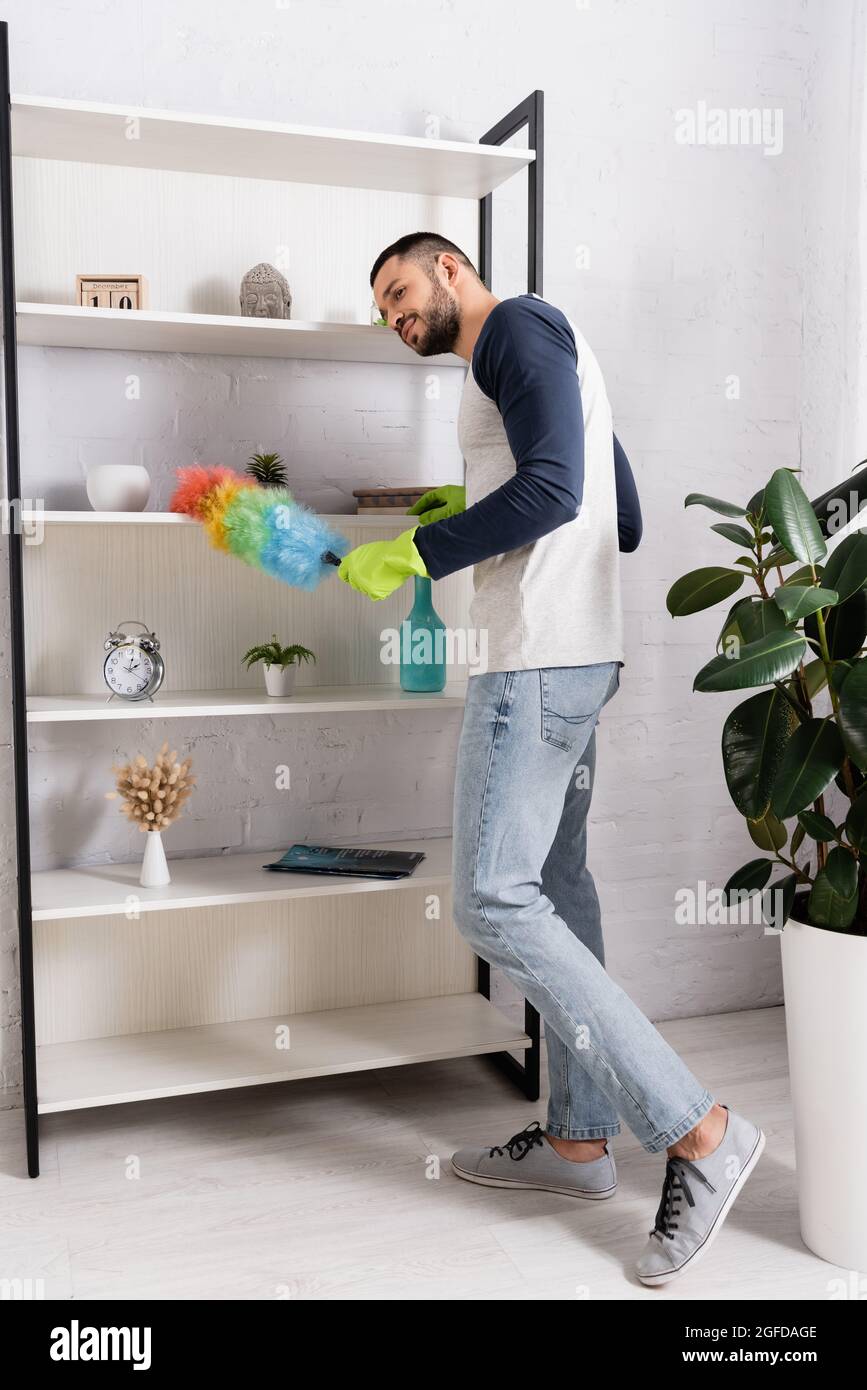 Young man cleaning cupboard with dust brush Stock Photo