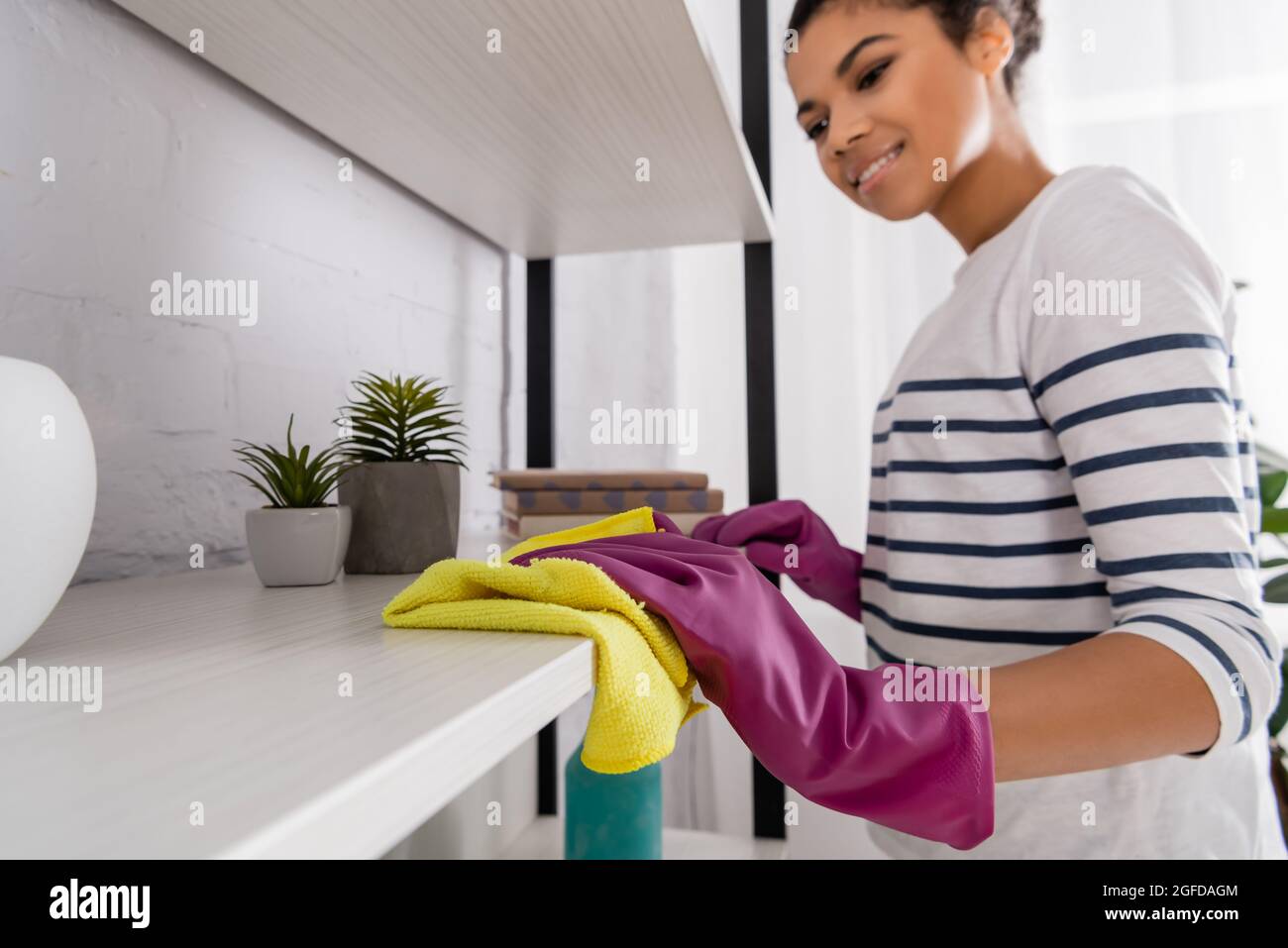Burred african american woman cleaning cupboard with rag Stock Photo