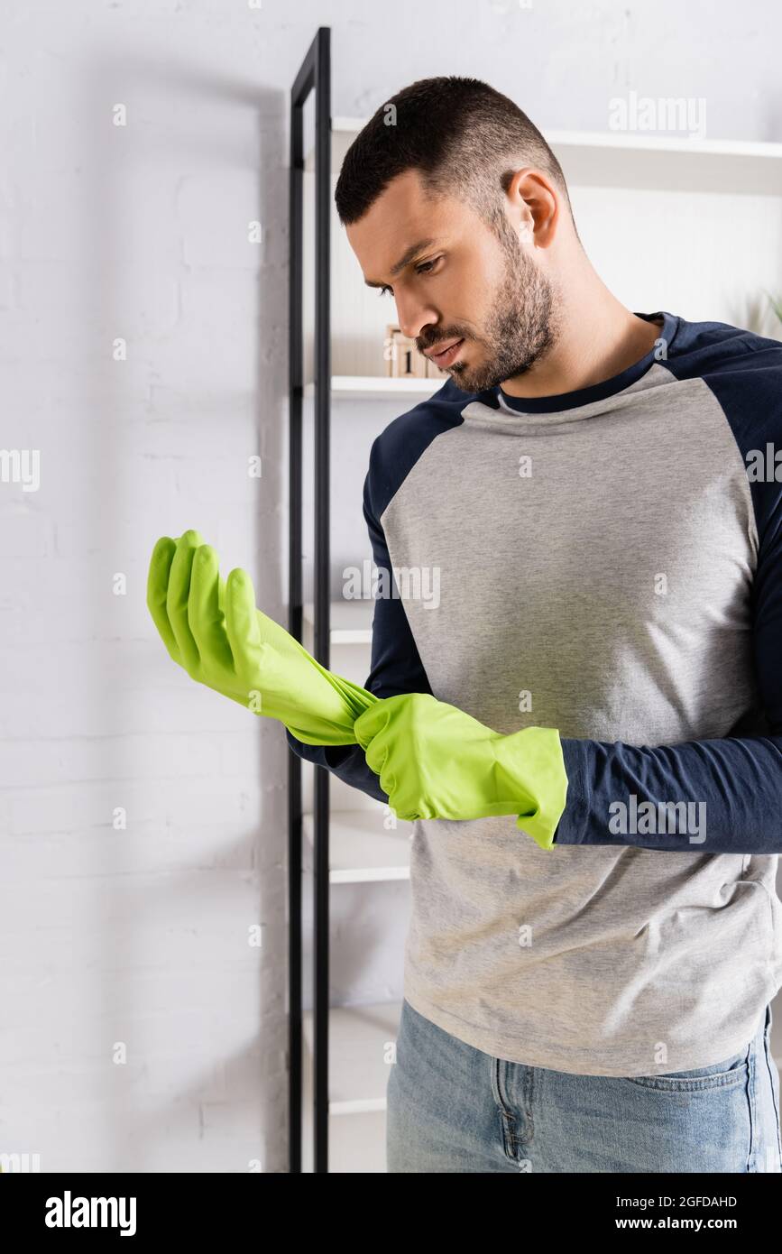 Young man wearing rubber gloves at home Stock Photo