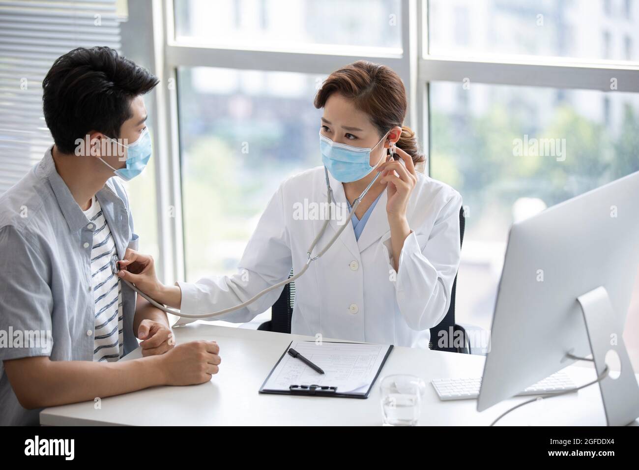 Doctor using stethoscope to examine patient Stock Photo