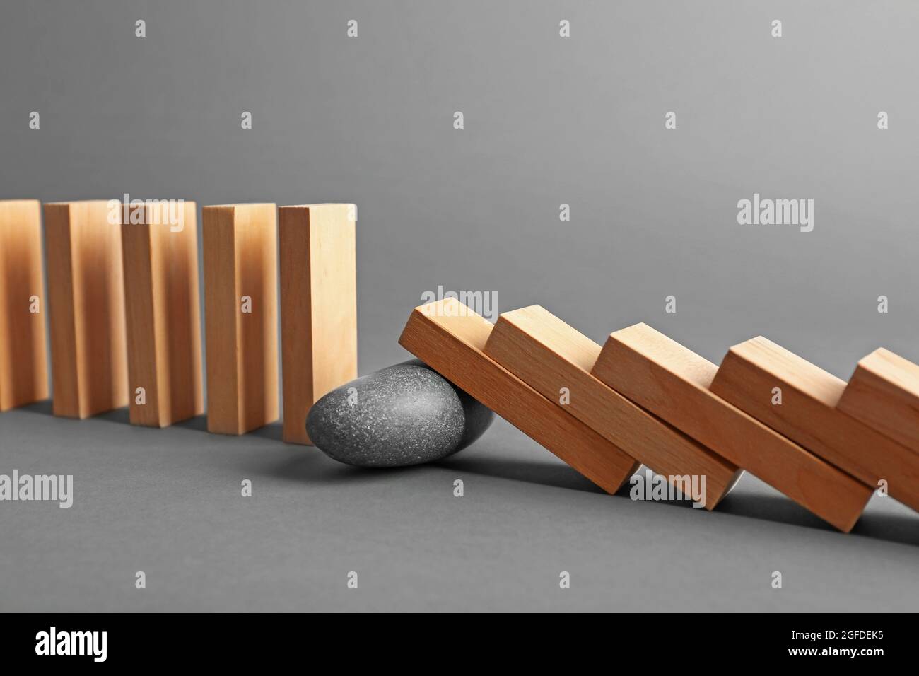Stone blocked row of falling dominoes on grey background Stock Photo ...