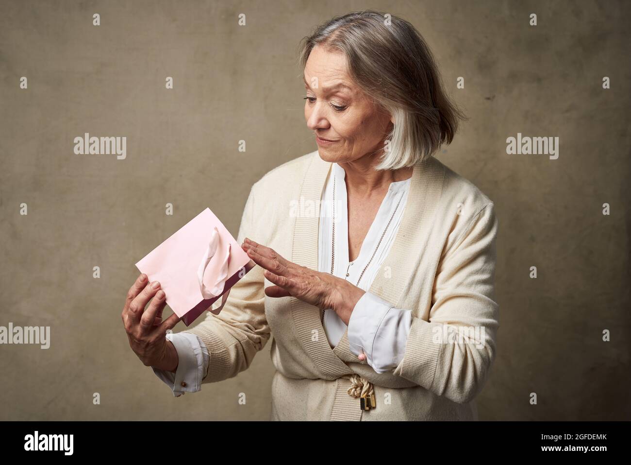 elderly woman in a dressing gown with a gift in her hands birthday care