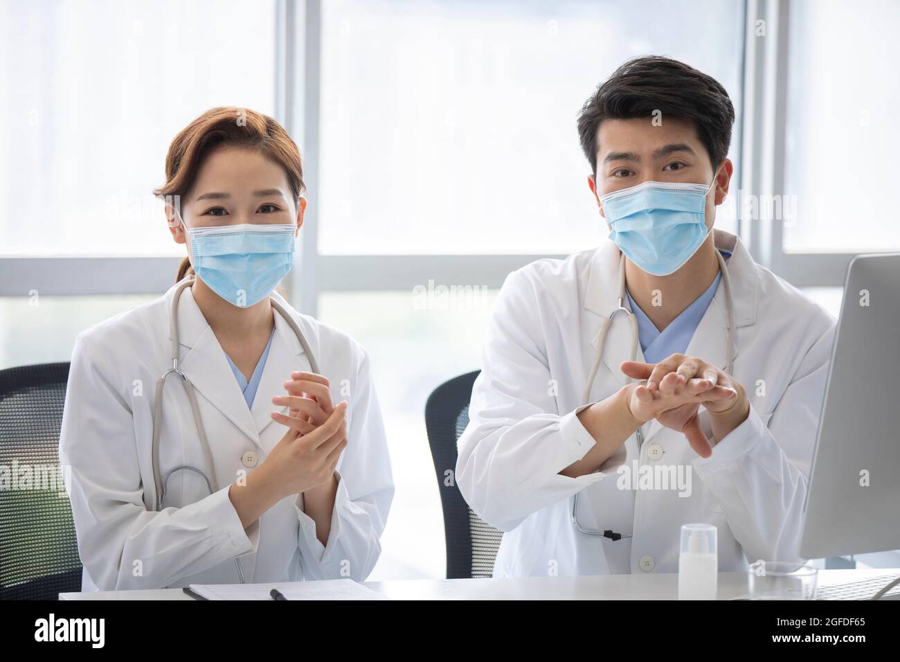 Young doctors using hand sanitizer in doctor's office Stock Photo