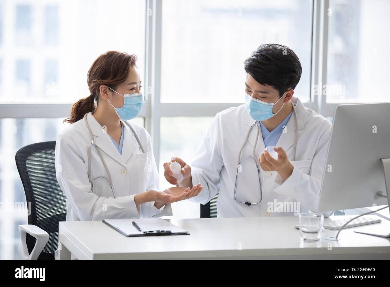 Young doctors using hand sanitizer in doctor's office Stock Photo