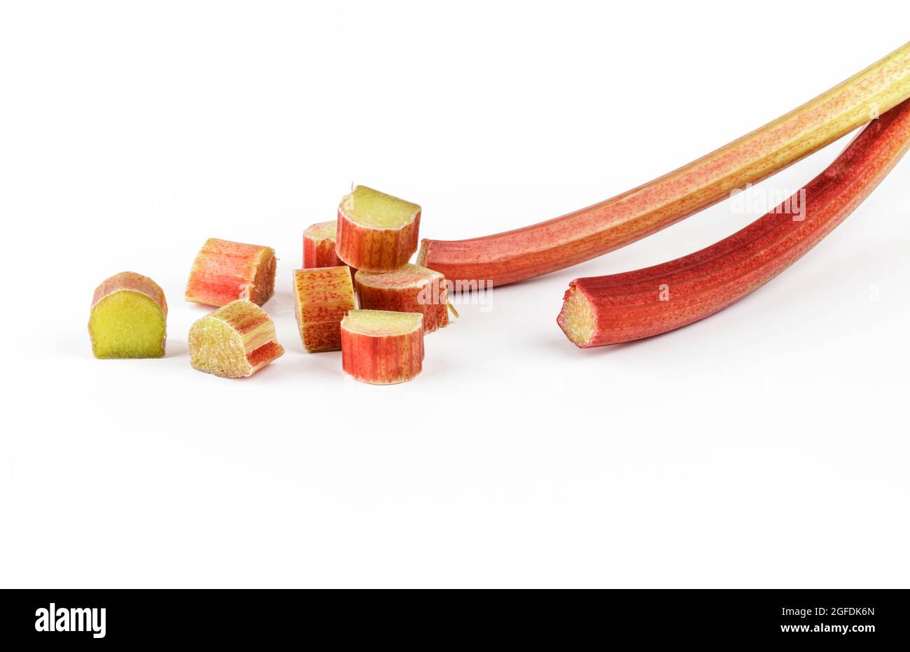 Rhubarb stalks and cut pieces of rhubarb on white background Stock Photo