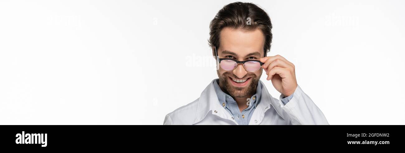 Doctor holding eyeglasses while smiling at camera isolated on white ...