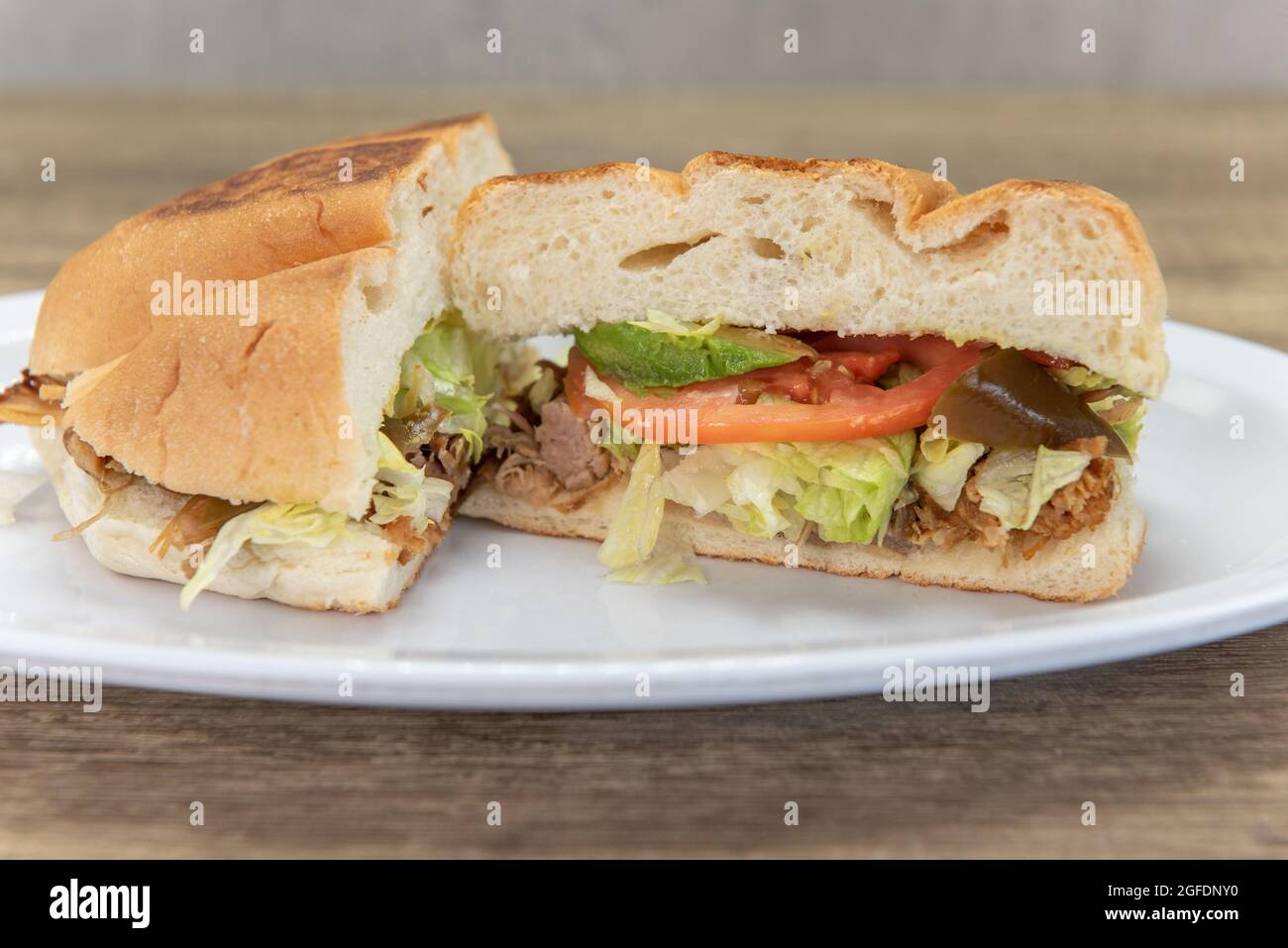 Hearty carnitas pork torta sandwich cut in half to show all the chopped