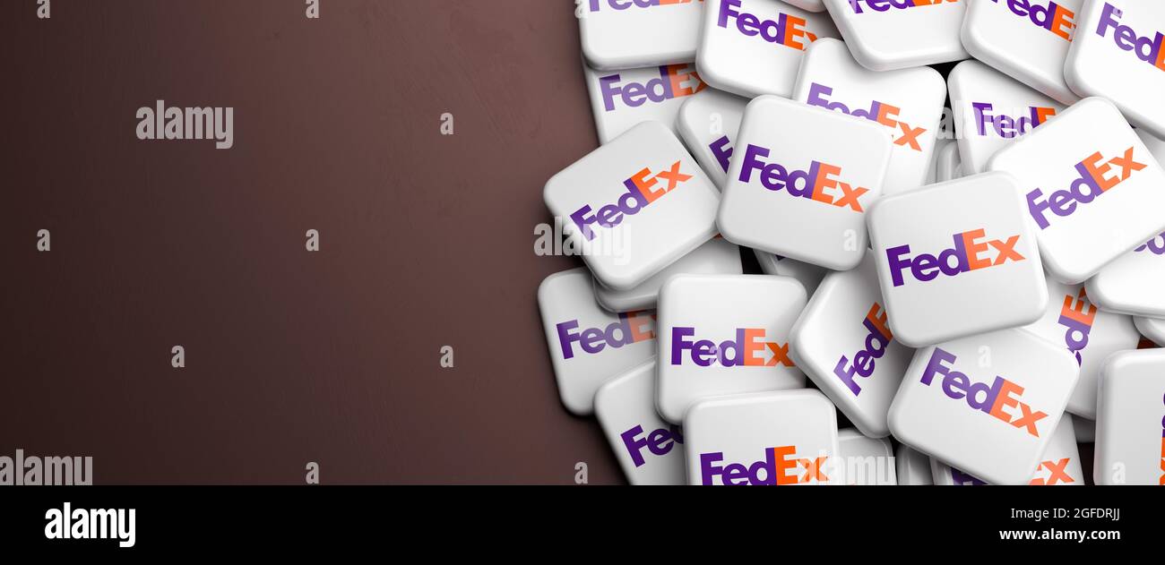 Logos of the shipping and delivery company FedEx Corporation on a heap on a table. Copy space. Web banner format. Stock Photo