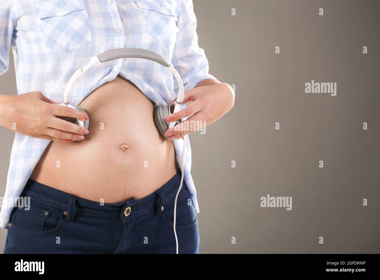 Pregnant woman holding headphones on belly Stock Photo