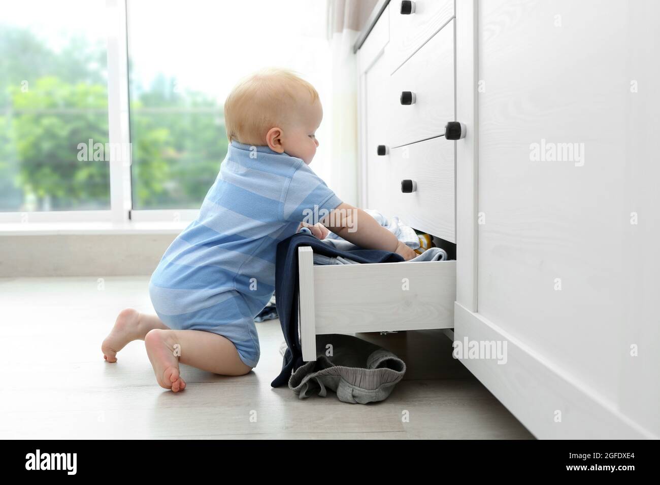 Baby throwing up clothes from wooden chest Stock Photo Alamy