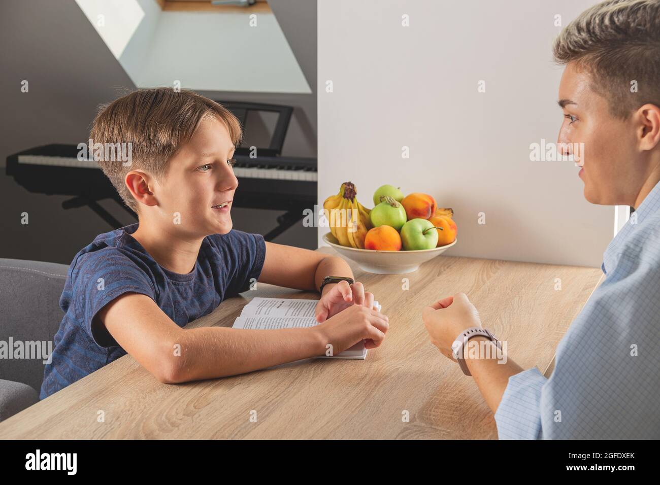 Kid boy doing homework at kitchen table with book Stock Photo