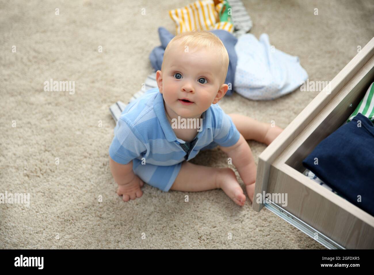 Baby throwing up clothes from wooden chest Stock Photo Alamy