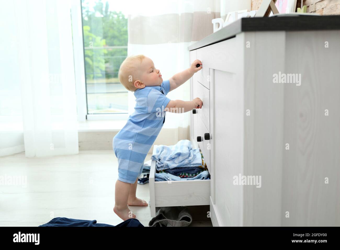 Baby throwing up clothes from wooden chest Stock Photo Alamy