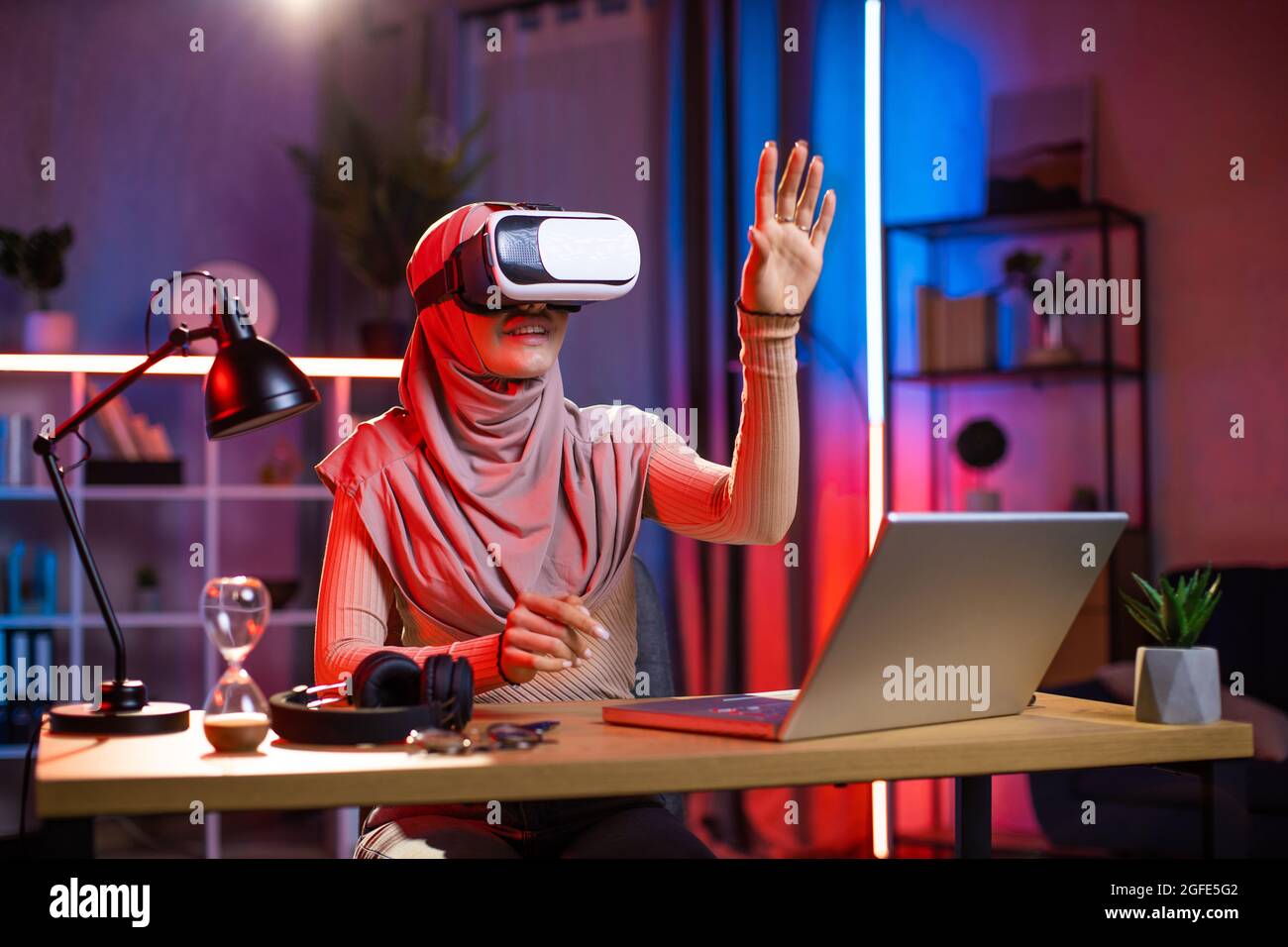 Modern smiling young Arab muslim woman in headscarf, using 3D augmented ...