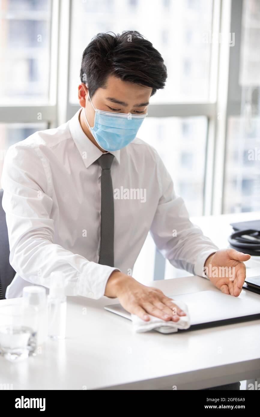Young businessman using disinfectant in office Stock Photo