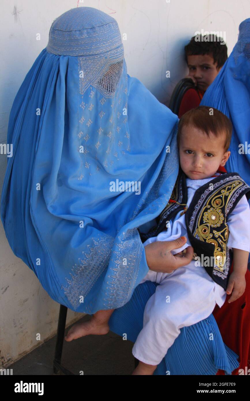 An Afghan mother, veiled by a burqa, holds her son on her lap as they wait to be seen at the Obdara clinic, where Provincial Reconstruction Team Panjshir medical personnel assisted a local midwife and nurse on Oct. 16. Stock Photo