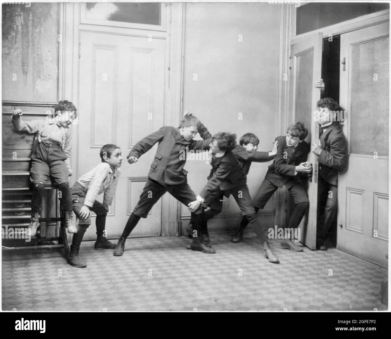 Fitz W. Guerin vintage photography - Two boys fighting in schoolroom while two others try to prevent teacher from entering room - 1907 Stock Photo