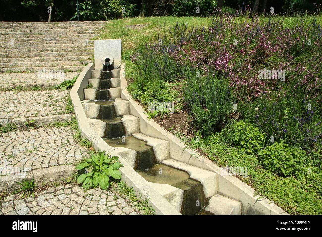 The concrete cascade by the stairs in the park made for the water stream. Design element or retention of the water for the birds. Stock Photo