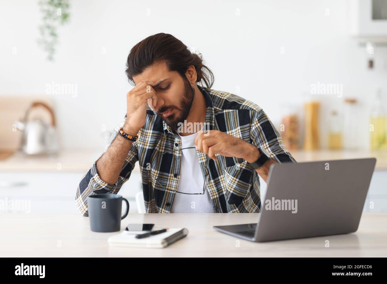 Tired middle-eastern man freelancer having difficulties at job Stock Photo