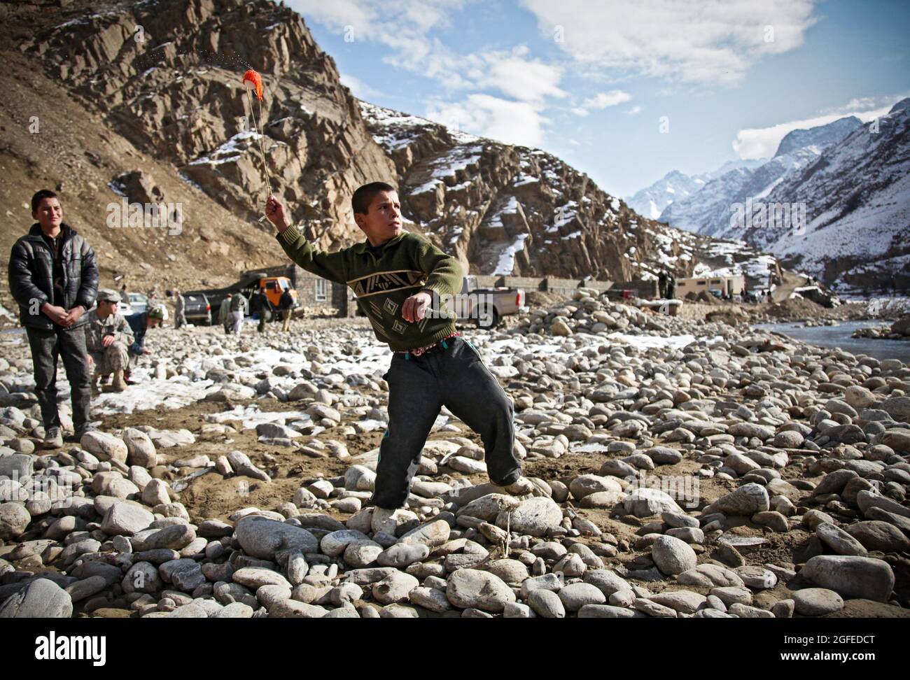 An Afghan child throws a snowball with a slingshot while playing next to  the river in the Dara District of Panjshir province, Afghanistan, Jan. 3,  2010 Stock Photo - Alamy