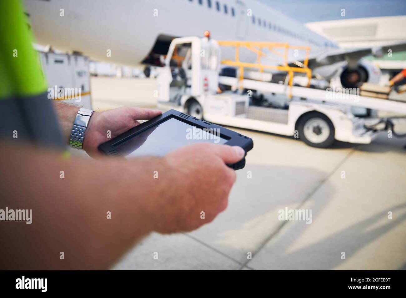 Member of ground staff preparing passenger airplane before flight. Worker using tablet against plane at airport. Stock Photo