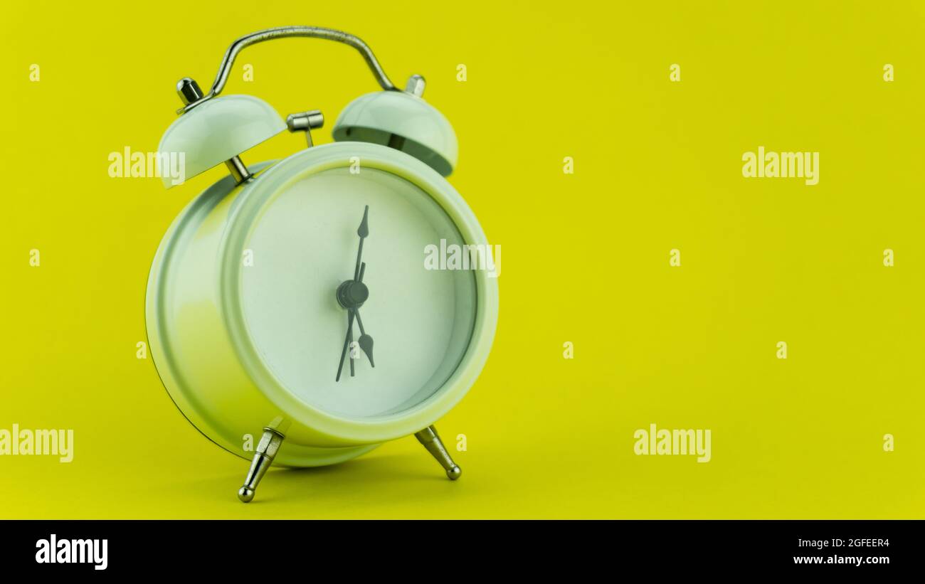 White alarm clock on yellow table background Stock Photo - Alamy