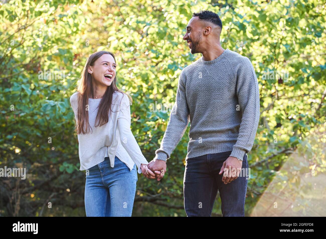Smiling young couple looking at each other in public park Stock Photo