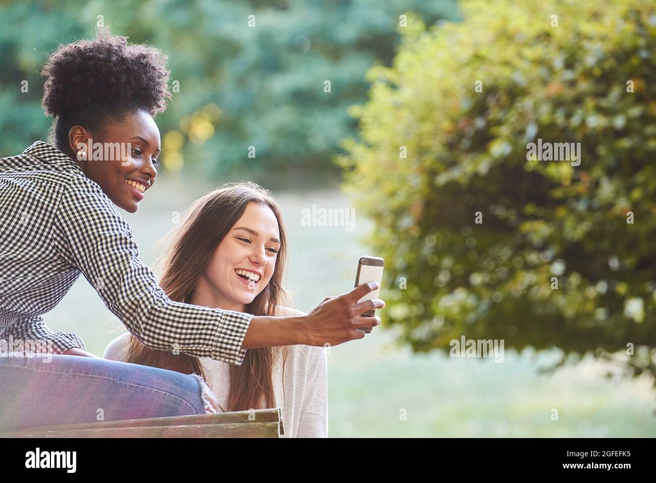Smiling young friends talking selfie on smartphone Stock Photo