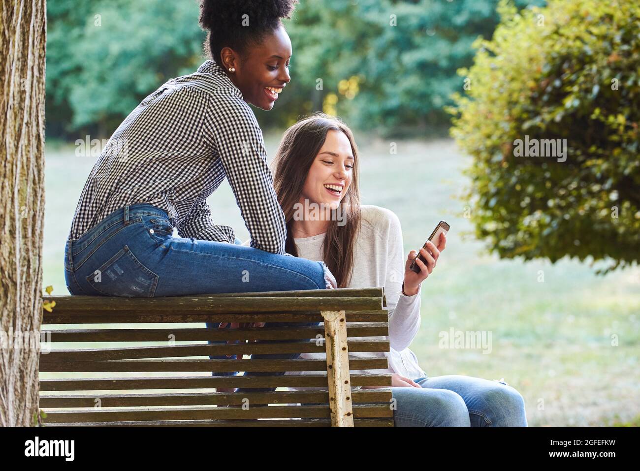 Smiling young friends using smartphone Stock Photo
