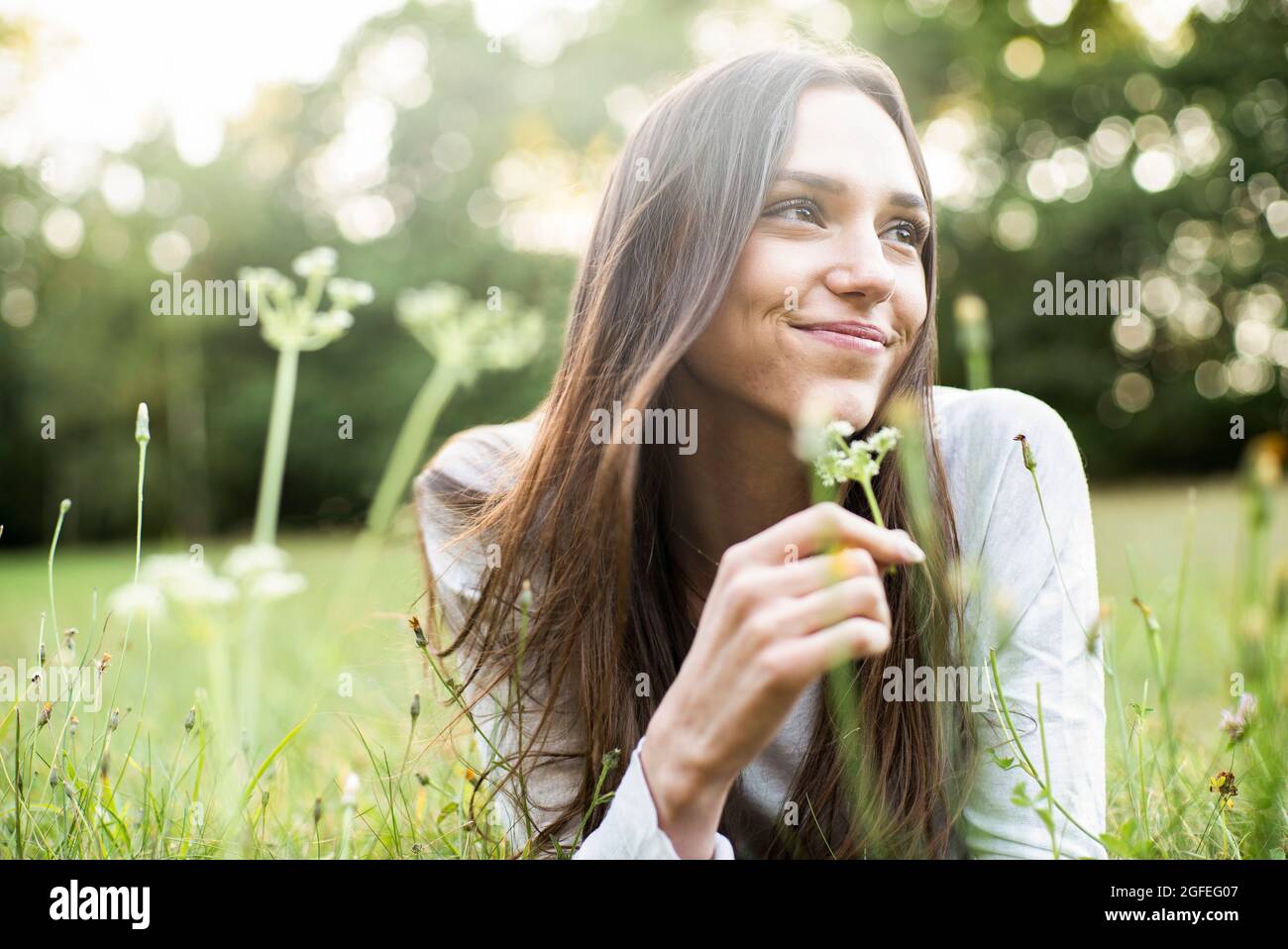 Portrait of smiling young woman lying in park Stock Photo