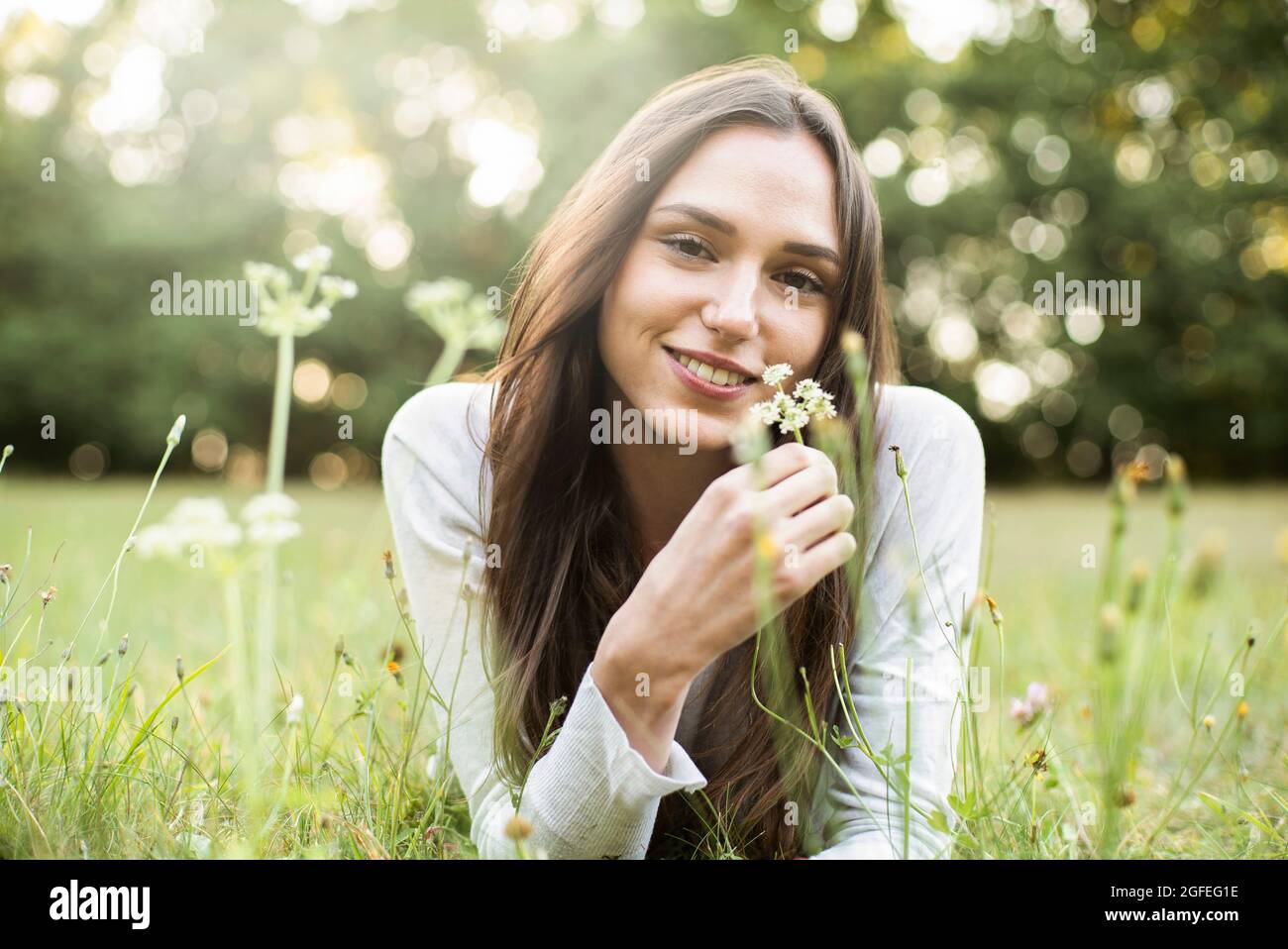 Portrait of smiling young woman lying in park Stock Photo
