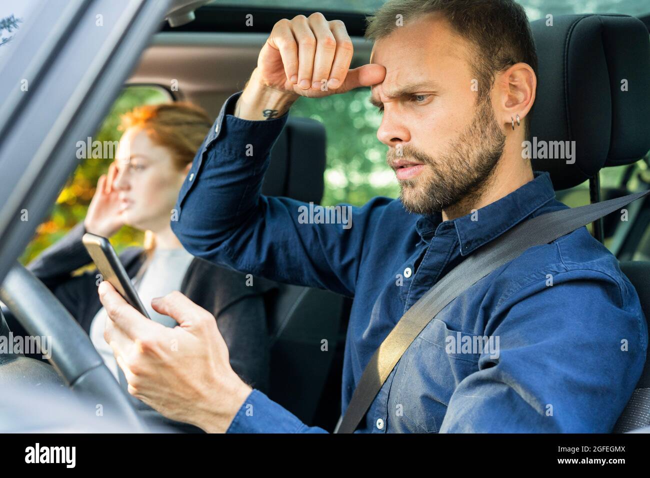 Frustrated young man using smart phone while driving a car Stock Photo