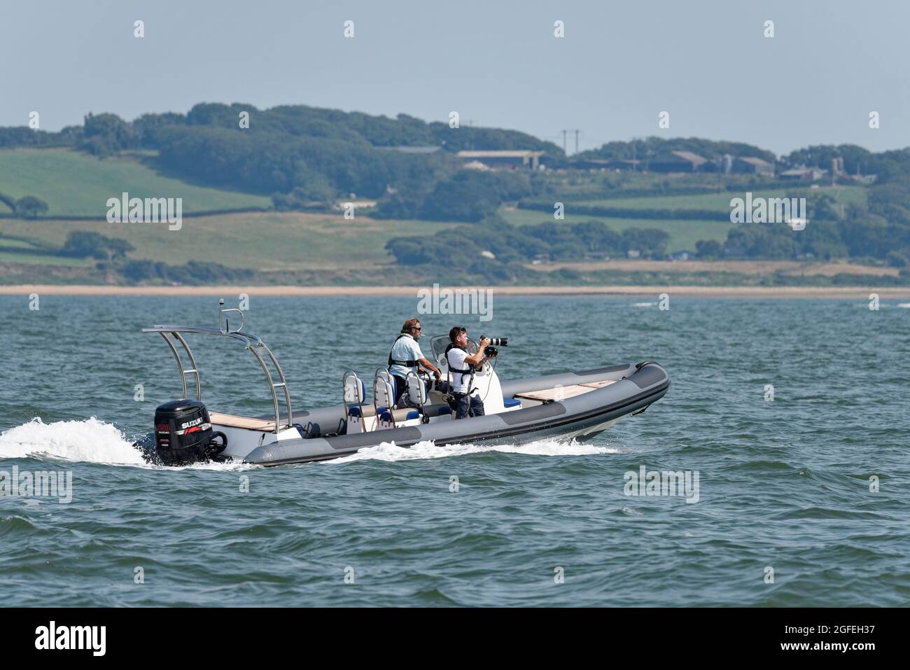 Photographer with a Gyro Stablised Canon Camera filming yacht racing in the Solent from his inflatble Rib motor boat Stock Photo