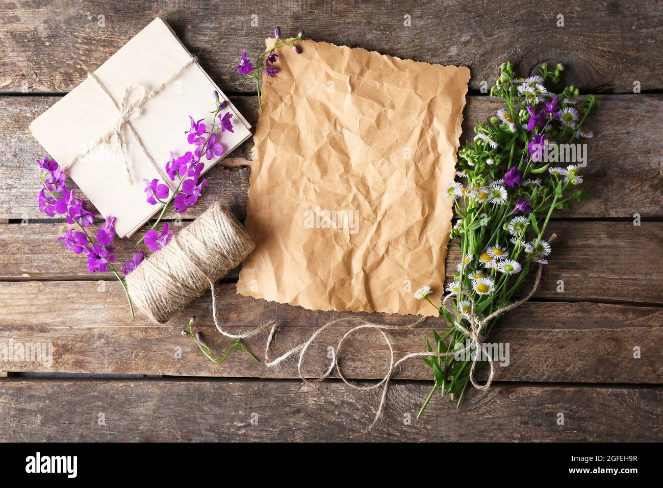 Crumpled paper, thread, envelope and bunch of delphinium and chamomile ...