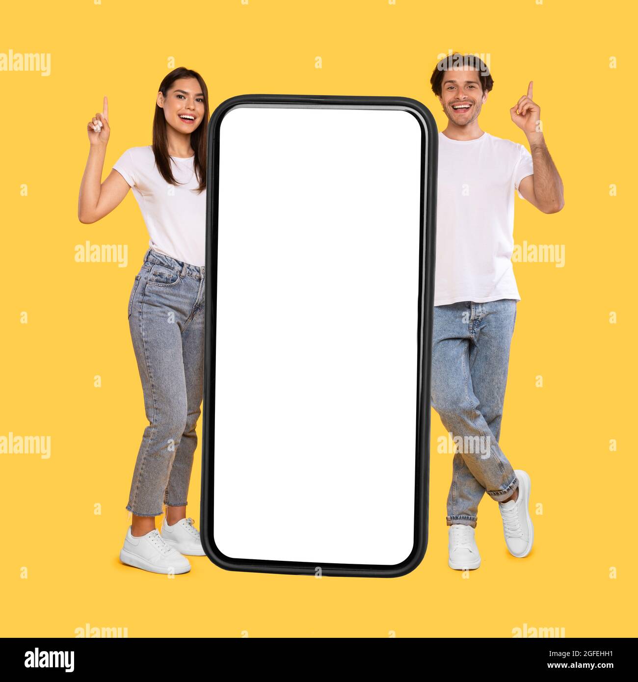 Couple standing next to big white empty smartphone screen Stock Photo