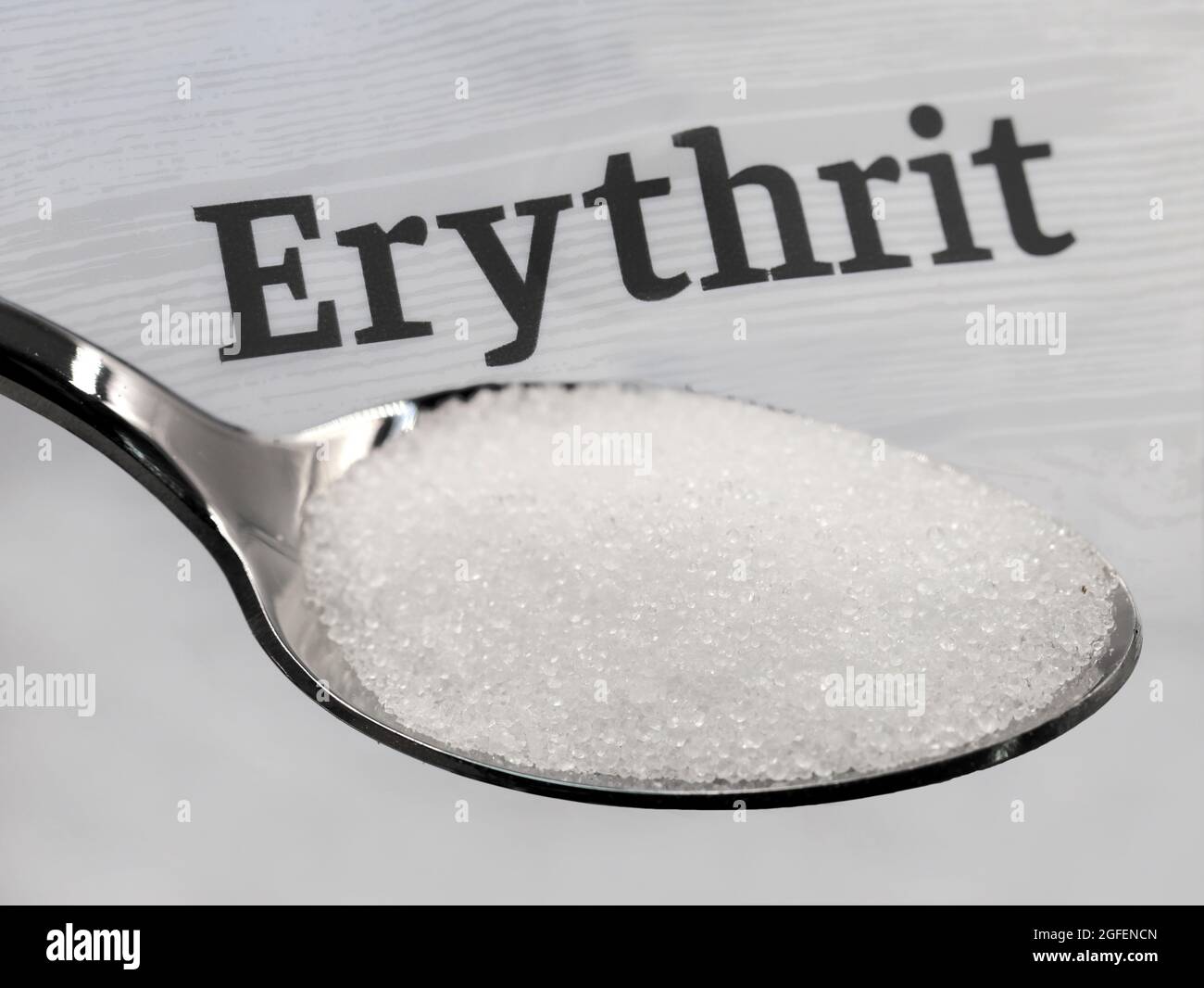 silver spoon with crystalline erythritol sugar in front of the word erythrit Stock Photo