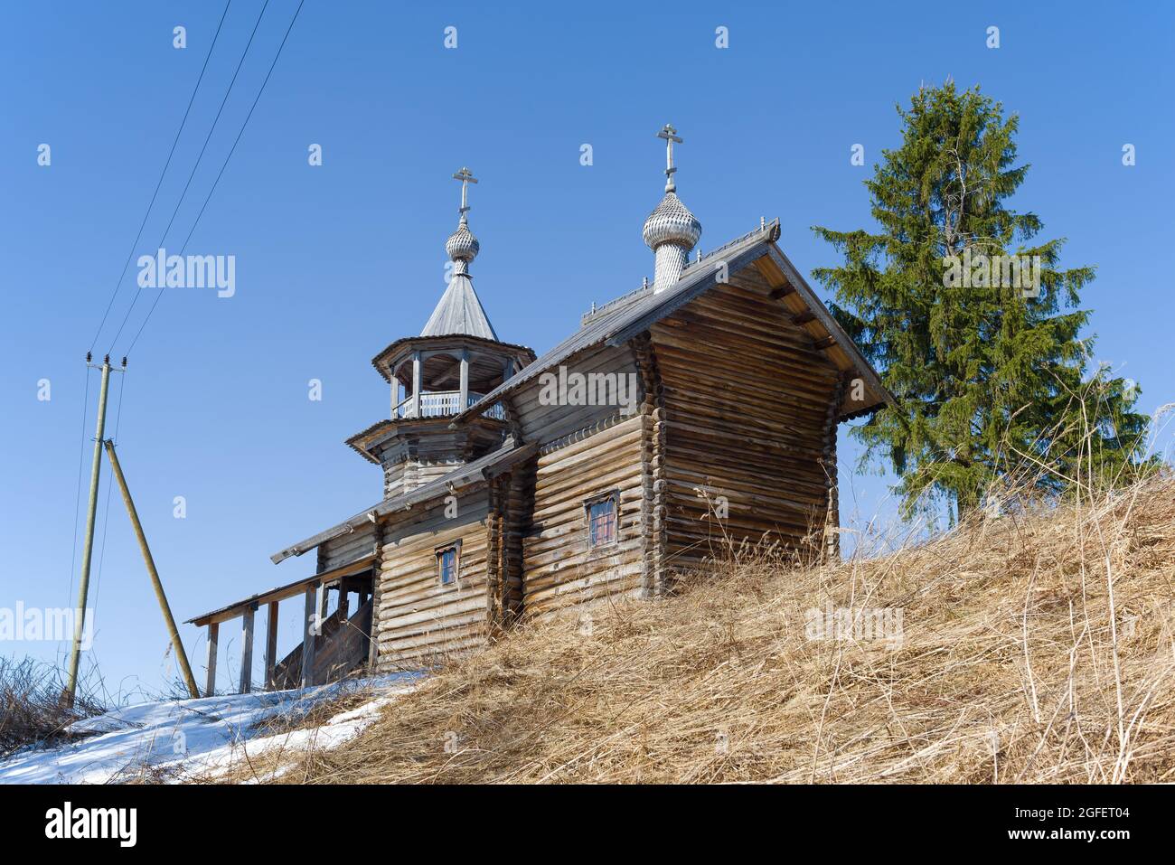 View of the ancient wooden chapel of the Nativity of the Virgin in the village of Manga on a sunny April day. Karelia, Russia Stock Photo