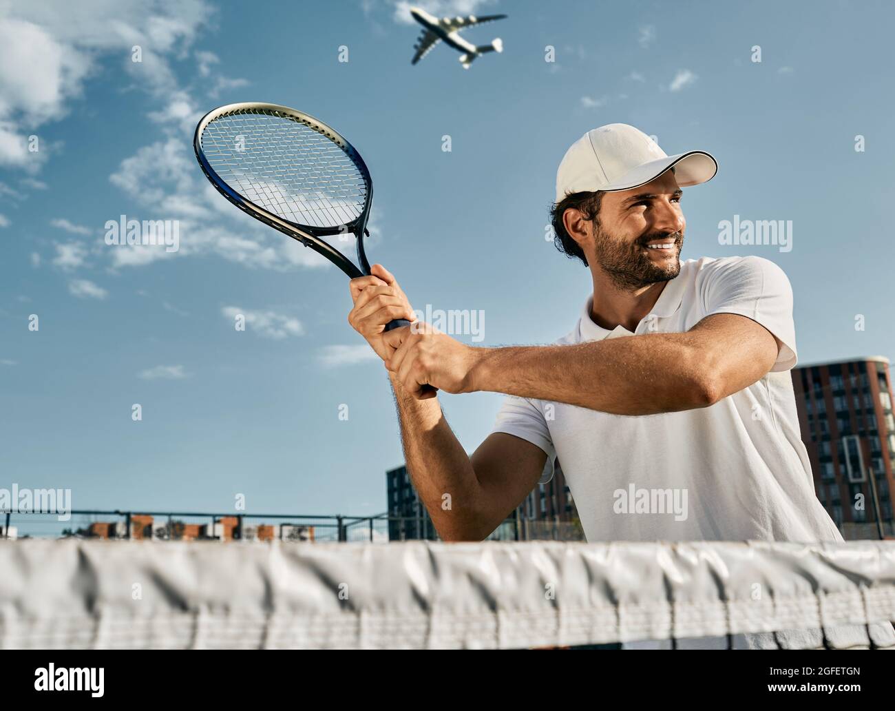 Handsome tennis player while match game with tennis racket in hands before shot over background of blue sky. Playing tennis game Stock Photo