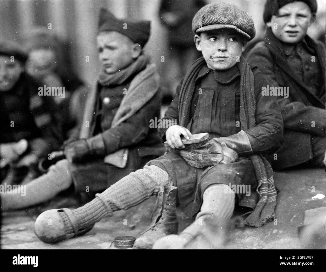 Shine 'em up –  a shoeshiner boy in Flanders. Poor orphan boys in Ypres. 1920. Stock Photo