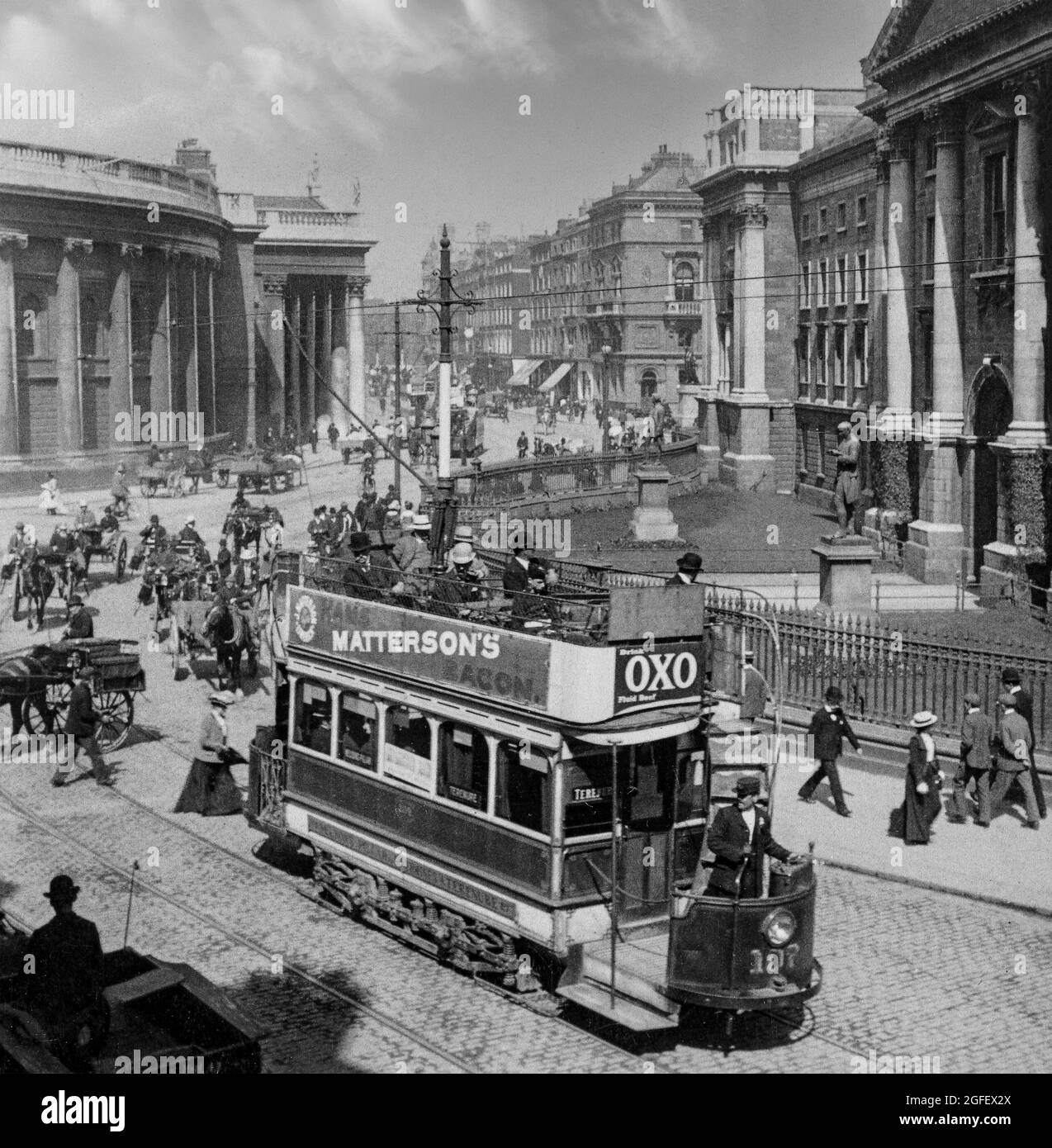 An early 20th century photograph of Trinity College (University) and the Bank of Ireland in College Green in Dublin City centre, Ireland, with people, horse drawn vehicles and the newly introduced electric trams. Stock Photo