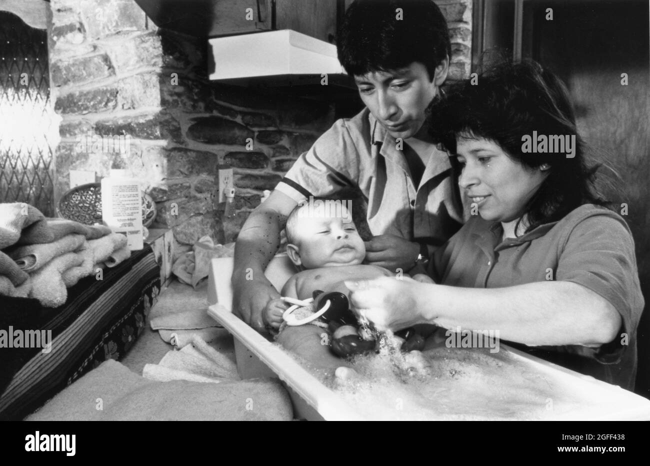 Austin Texas USA, circa 1989: Hispanic parents bathing their baby, MR XRE-0336, 0337   MR OK  original in color   ©Bob Daemmrich Stock Photo
