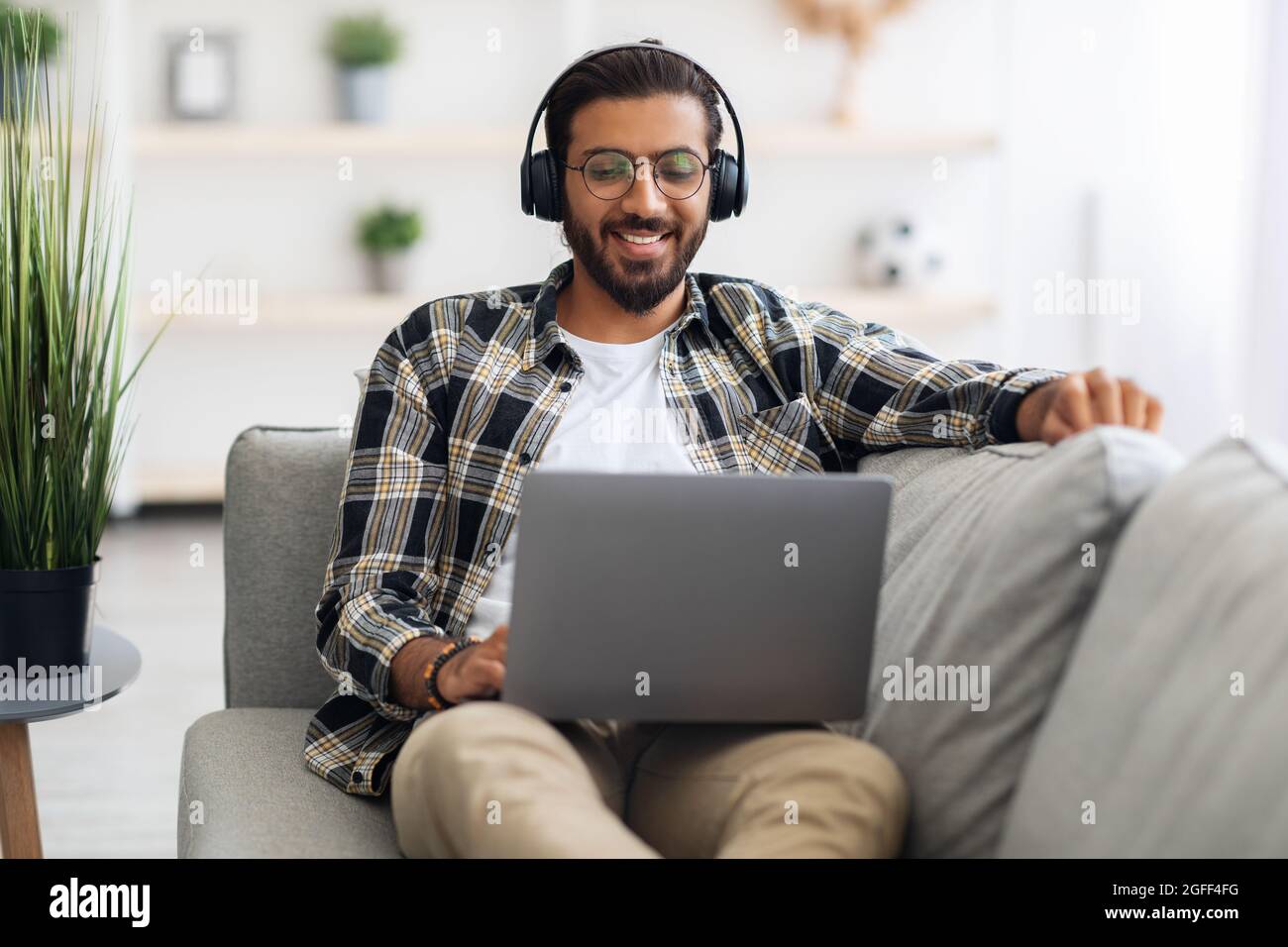 Relaxed middle-eastern guy watching movie online, using laptop Stock Photo